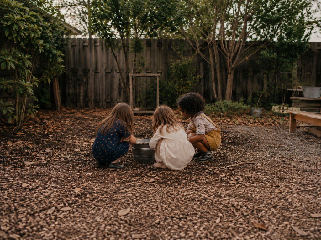 A child playing outdoors with two other children, showing social connection and shared play beyond sibling relationships.